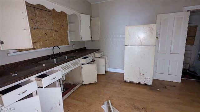 kitchen featuring white cabinetry, sink, hardwood / wood-style floors, and white refrigerator