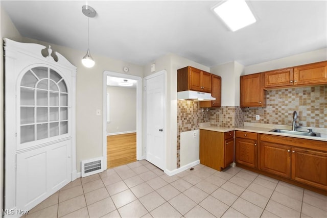 kitchen featuring light tile patterned flooring, pendant lighting, tasteful backsplash, and sink