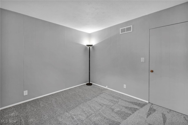 carpeted empty room with a textured ceiling