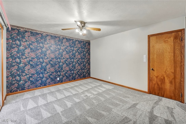 carpeted spare room featuring a textured ceiling and ceiling fan