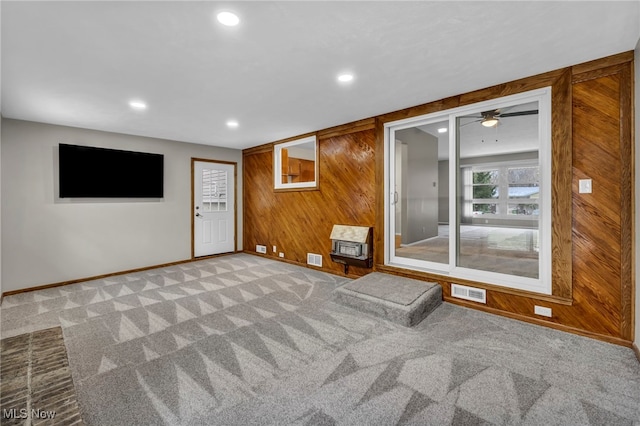 spare room featuring light colored carpet, ceiling fan, and wood walls