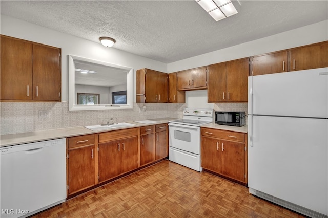 kitchen with a textured ceiling, white appliances, sink, and light parquet flooring