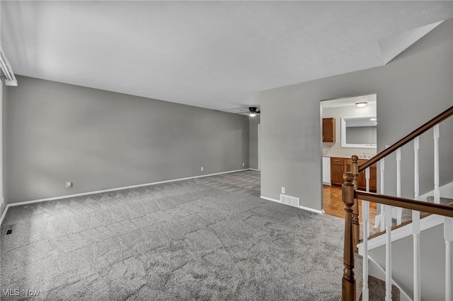 unfurnished living room with ceiling fan and carpet