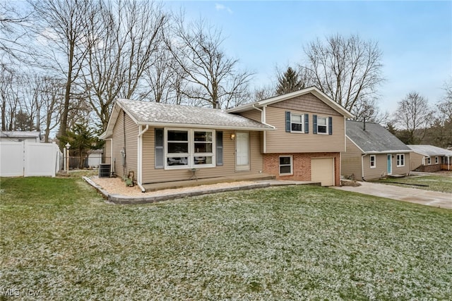 split level home with cooling unit, a garage, and a front lawn