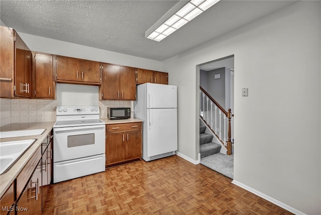 kitchen featuring sink, backsplash, a textured ceiling, white appliances, and light parquet flooring