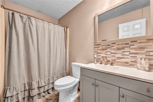 bathroom with curtained shower, tasteful backsplash, a textured ceiling, toilet, and vanity