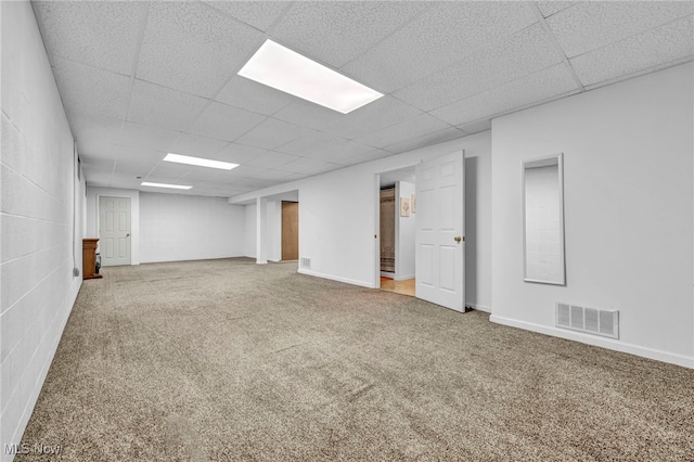 basement with a paneled ceiling and carpet floors