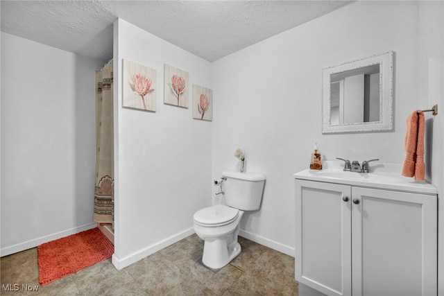 bathroom with vanity, toilet, and a textured ceiling