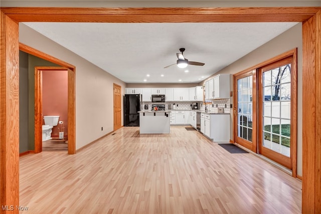 kitchen featuring black appliances, white cabinets, ceiling fan, light wood-type flooring, and tasteful backsplash