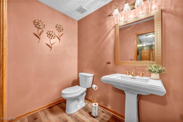 bathroom with hardwood / wood-style floors, a textured ceiling, and toilet