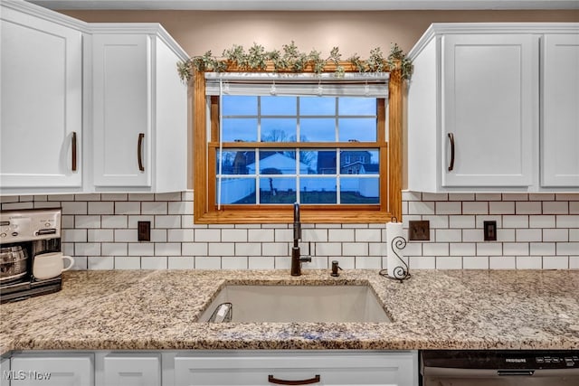 kitchen featuring decorative backsplash, dishwasher, white cabinetry, and sink