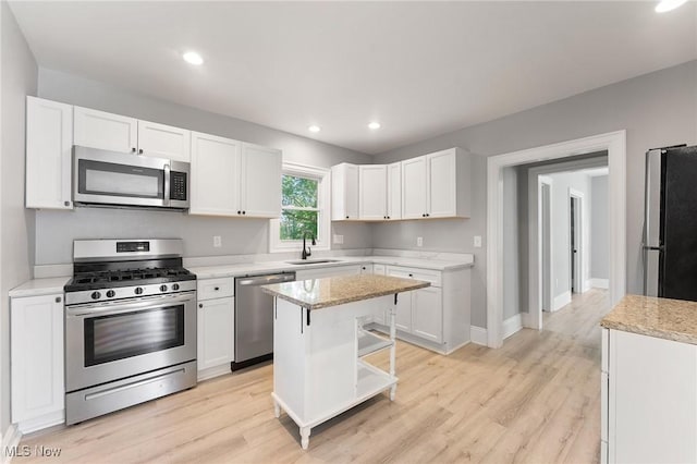 kitchen featuring a center island, sink, light hardwood / wood-style floors, white cabinetry, and stainless steel appliances