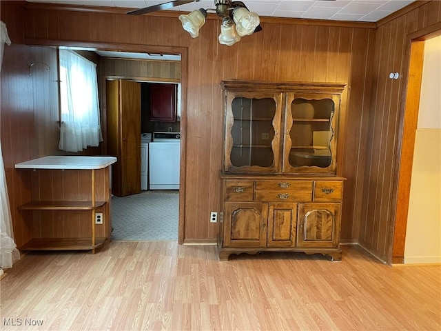 hallway featuring washer and clothes dryer, wood walls, and light wood-type flooring