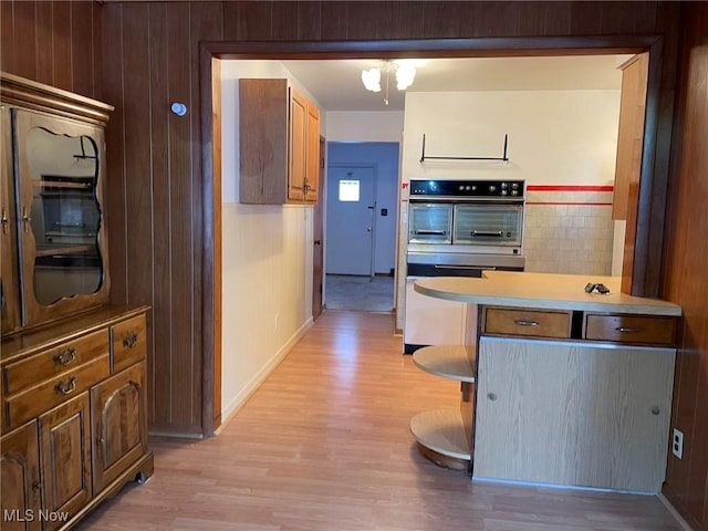 kitchen with ceiling fan, a kitchen breakfast bar, light wood-type flooring, and multiple ovens