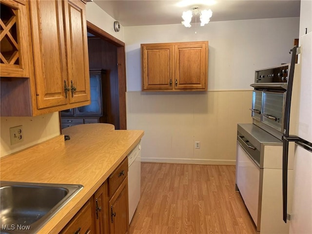 kitchen featuring white dishwasher, oven, light wood-type flooring, and sink