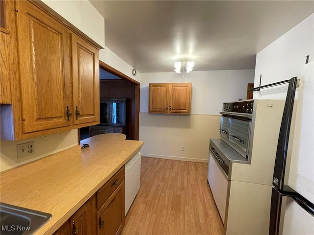 kitchen featuring sink, fridge, an inviting chandelier, light wood-type flooring, and white dishwasher