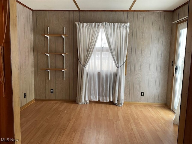 empty room with light wood-type flooring and wood walls