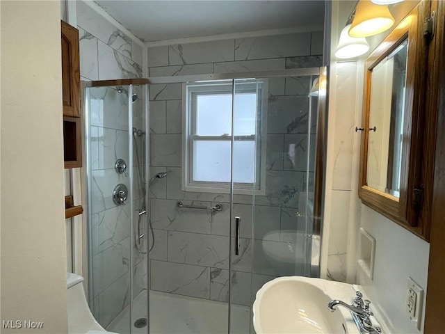 bathroom with sink and a shower with door