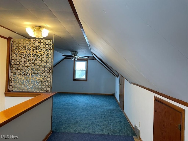 additional living space featuring vaulted ceiling, dark colored carpet, and ceiling fan