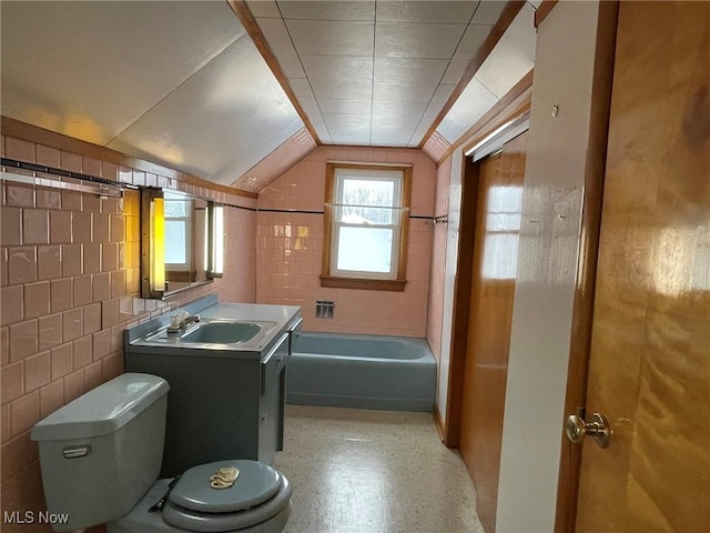 bathroom featuring toilet, vanity, tile walls, and vaulted ceiling