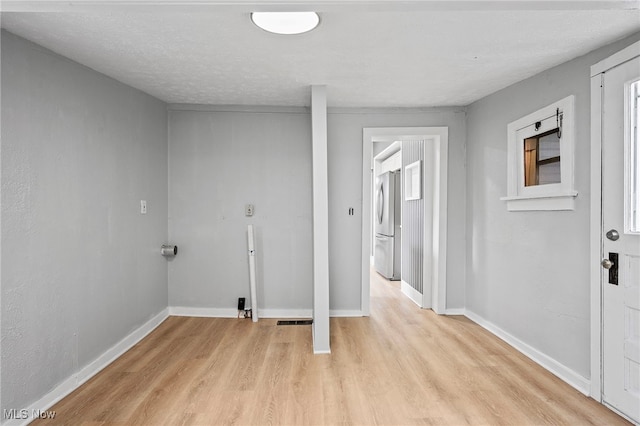 laundry room with a textured ceiling and light hardwood / wood-style flooring