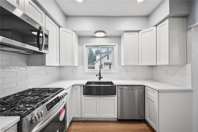 kitchen featuring white cabinets, decorative backsplash, sink, and appliances with stainless steel finishes