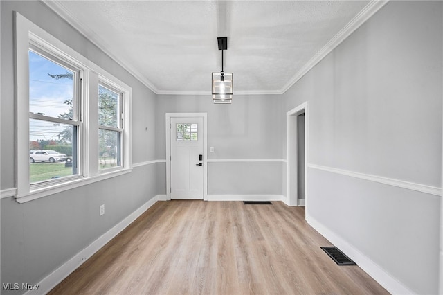 unfurnished dining area with a textured ceiling, light hardwood / wood-style floors, and ornamental molding