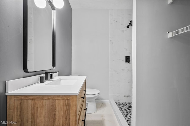 bathroom with tiled shower, vanity, and toilet