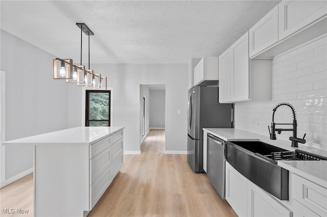 kitchen with sink, a kitchen island, decorative backsplash, white cabinets, and appliances with stainless steel finishes