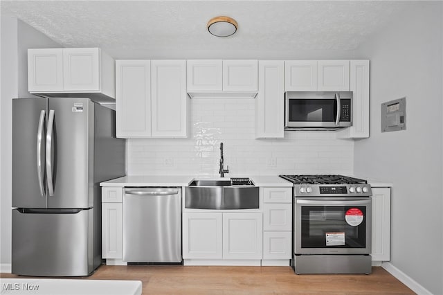 kitchen featuring light hardwood / wood-style floors, sink, white cabinetry, and stainless steel appliances