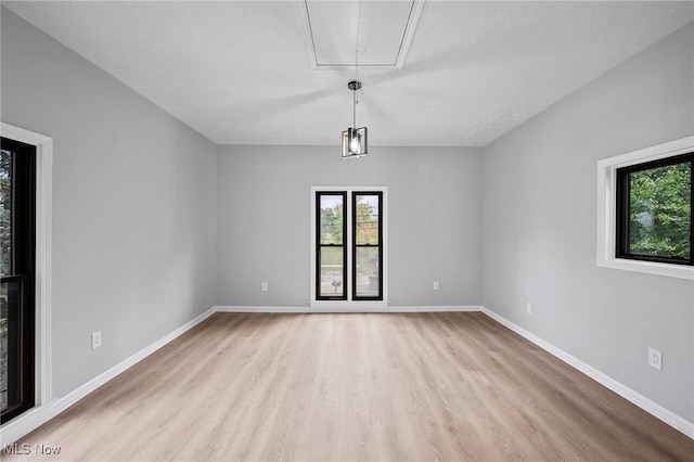 unfurnished room featuring a textured ceiling and light hardwood / wood-style flooring