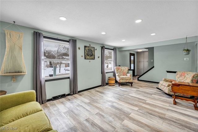 sitting room with a textured ceiling, light wood-type flooring, and a wealth of natural light