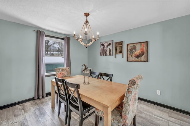 dining room with a textured ceiling, light hardwood / wood-style flooring, and an inviting chandelier