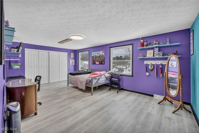 bedroom featuring light hardwood / wood-style floors and a textured ceiling