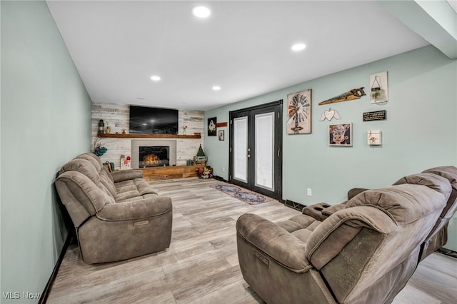 living room featuring light wood-type flooring, a fireplace, and french doors