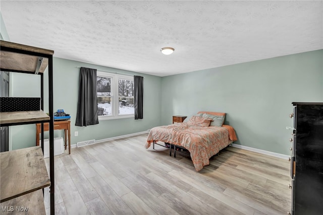 bedroom with light wood-type flooring and a textured ceiling