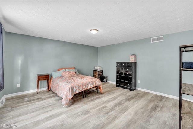 bedroom featuring light wood-type flooring and a textured ceiling