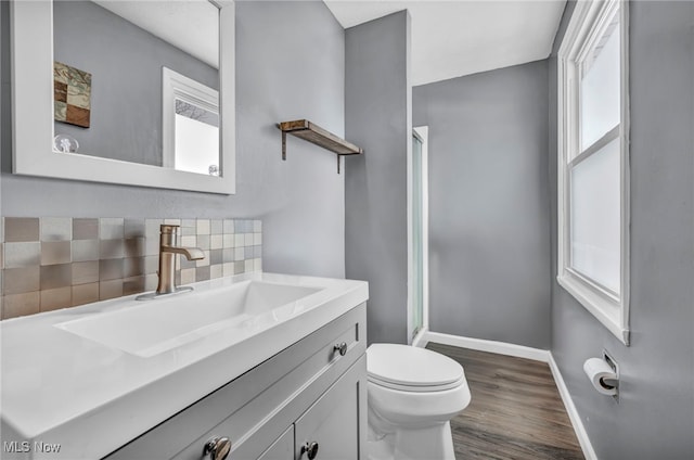 bathroom with backsplash, hardwood / wood-style floors, toilet, a shower with door, and vanity