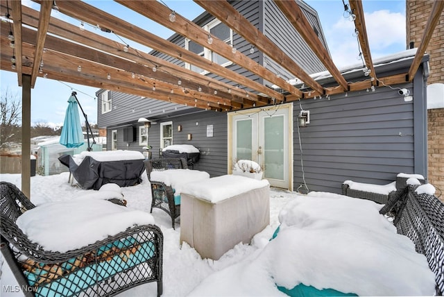 snow covered patio with area for grilling, a pergola, and french doors