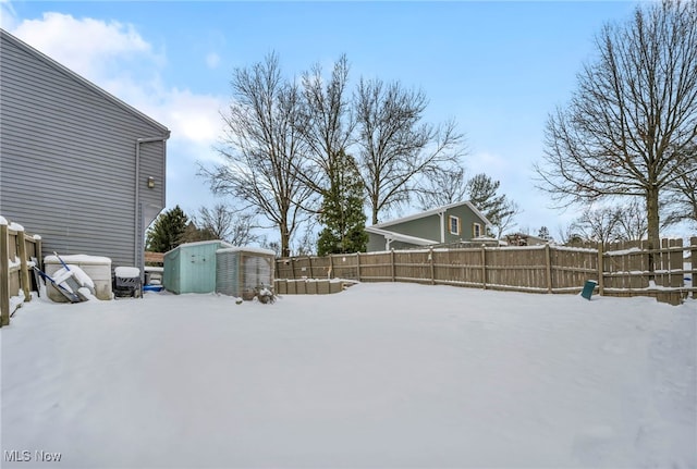 yard layered in snow featuring a storage unit