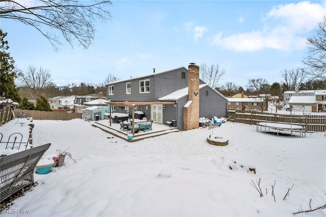 snow covered rear of property with a trampoline