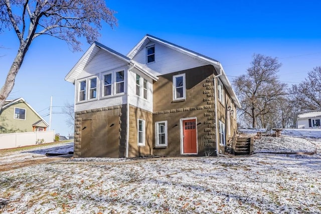 snow covered back of property featuring a garage