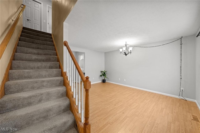 staircase with hardwood / wood-style flooring and a chandelier