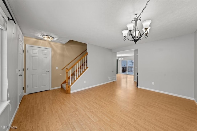 unfurnished living room with a notable chandelier and light hardwood / wood-style flooring