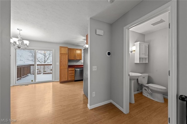 interior space featuring hardwood / wood-style flooring, ceiling fan with notable chandelier, toilet, and a textured ceiling