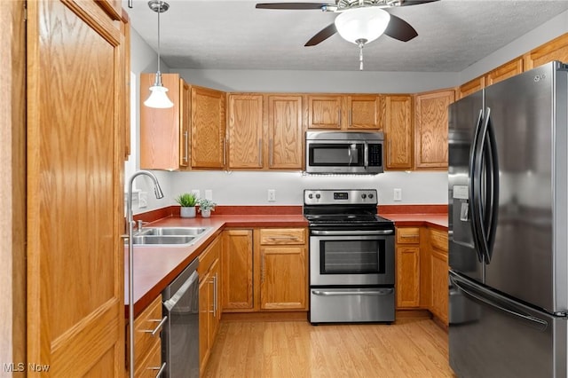 kitchen with ceiling fan, sink, stainless steel appliances, light hardwood / wood-style flooring, and decorative light fixtures