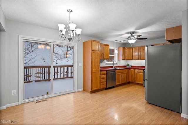 kitchen featuring pendant lighting, ceiling fan with notable chandelier, sink, and stainless steel appliances