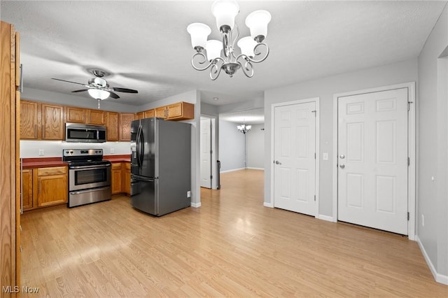 kitchen with appliances with stainless steel finishes, ceiling fan with notable chandelier, light hardwood / wood-style floors, and a textured ceiling