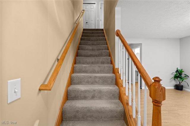 stairway featuring hardwood / wood-style flooring and a textured ceiling