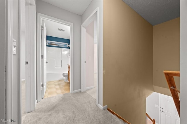 hallway with light carpet and a textured ceiling